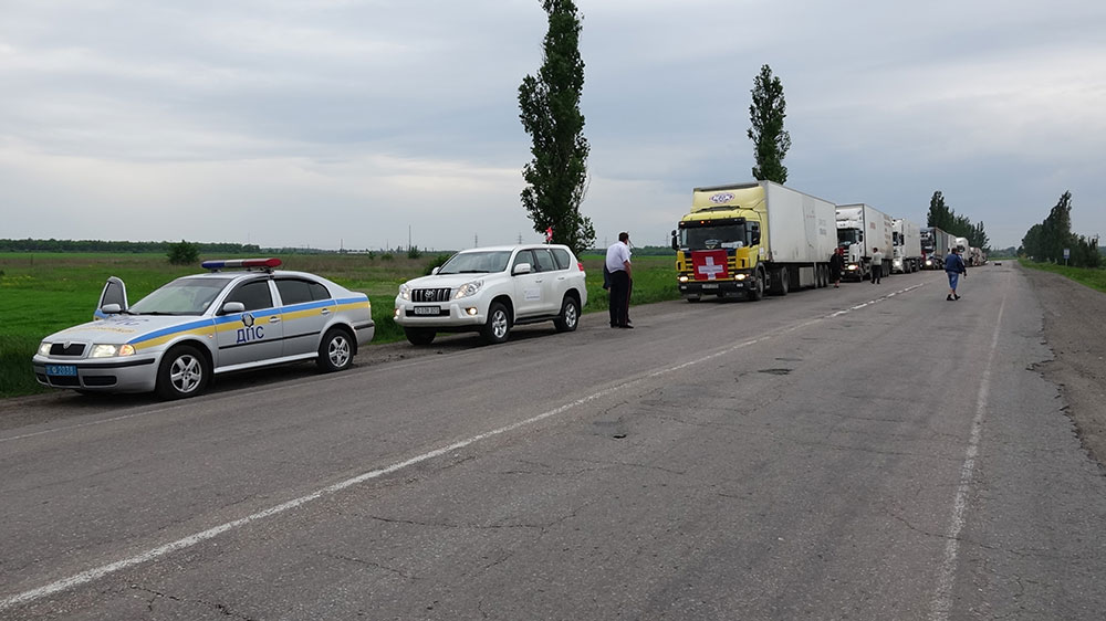 Alcuni camion circolano con la bandiera svizzera su una strada ucraina.