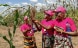 Three women stand around a plant inspecting its seeds.
