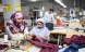 Tres instructores forman a tres costureras de una fábrica textil en sus lugares de trabajo