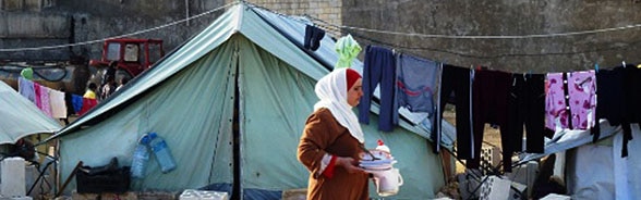 Eine Frau wandert vor einen Flüchtlingszelt.  