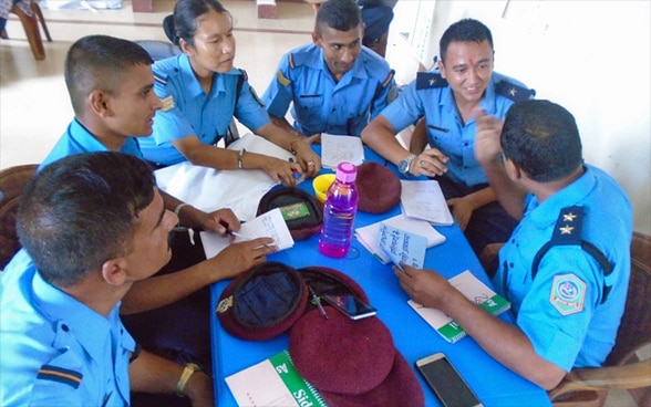 Five male and one woman police officer discuss a case