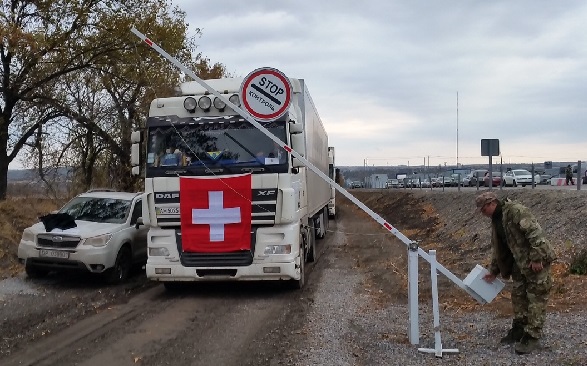 Un soldado levanta una barrera para dar paso a un camión de la Ayuda Humanitaria suiza.