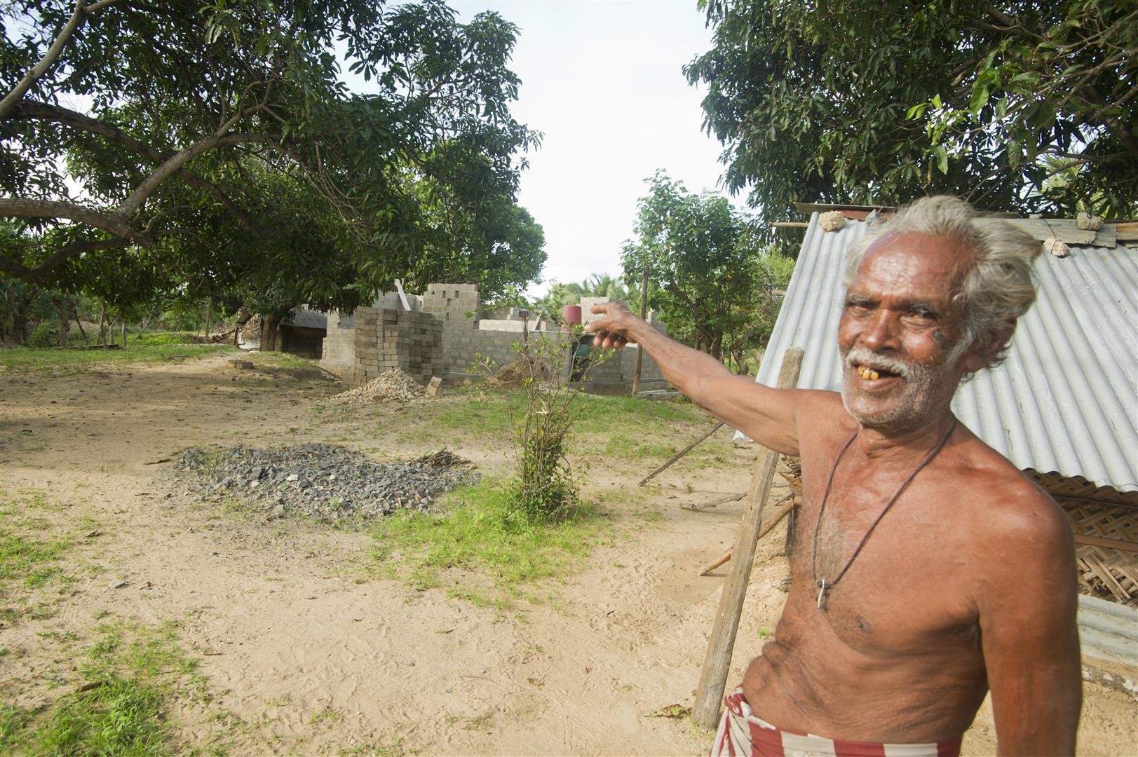 Ein Mann zeigt auf sein Haus, das wieder aufgebaut wird.
