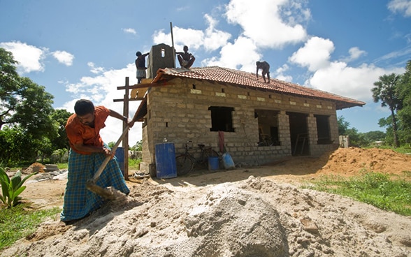 Un esrilanqués trabaja con una pala frente a una vivienda en construcción.