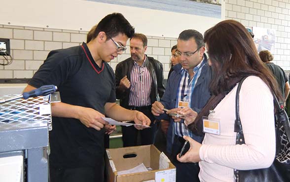 An apprentice at Schindler Lifts explains to the Honduran delegation what he is currently working on