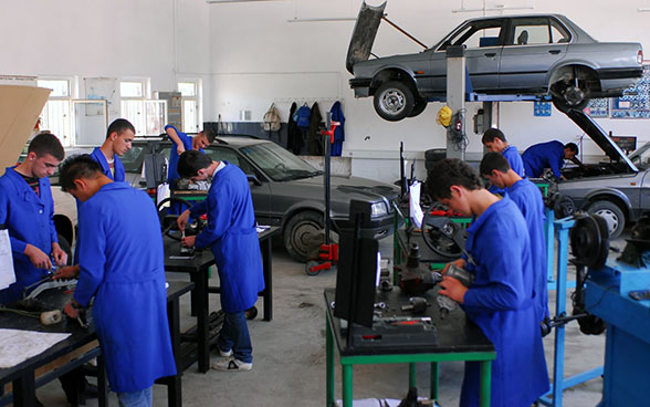 Aprendices de mecánica reparan automóviles en un taller de formación