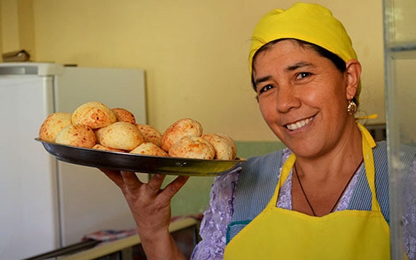 Doña Silvia posa in tenuta da lavoro con un vassoio di panini appena sfornati. 