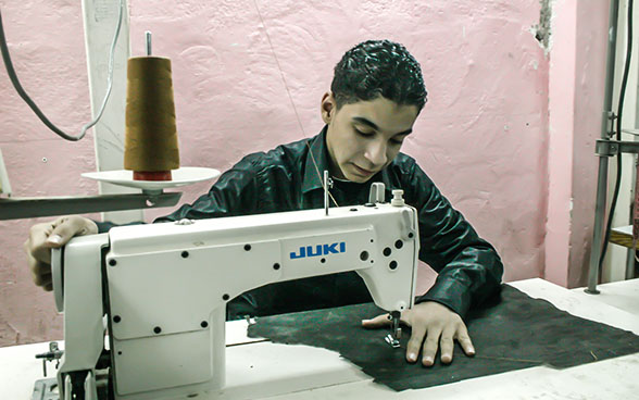 Un aprendiz cosiendo una tela con una máquina de coser