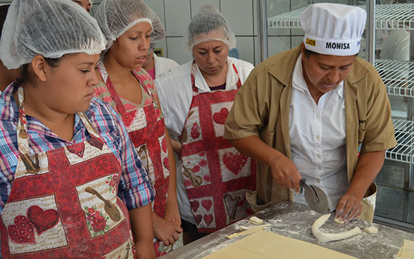 Apprentice bakers listen to the instructor's explanations.