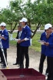 Apprentices standing in a park learn how to use a theodolite