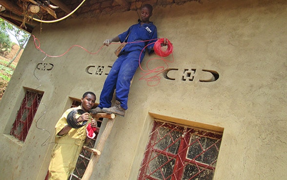 Joseph Ntirandekura and a colleague work in front of a house