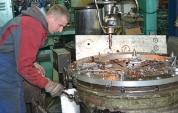 A young man stands at a workbench operating a lever.