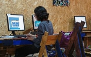 Une femme installée devant un ordinateur suit les cours de la plate-force UN CC:Learn. 