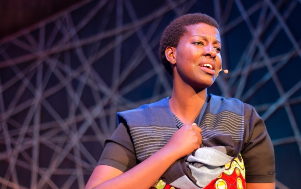  An artist wearing a microphone clasps a fist to her chest as tears run down her cheeks.