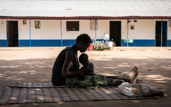 Una giovane madre culla il suo bimbo malnutrito fuori dal centro di stabilizzazione sostenuto dall’UNICEF a Malualkon, Aweil, Sudan del Sud.  