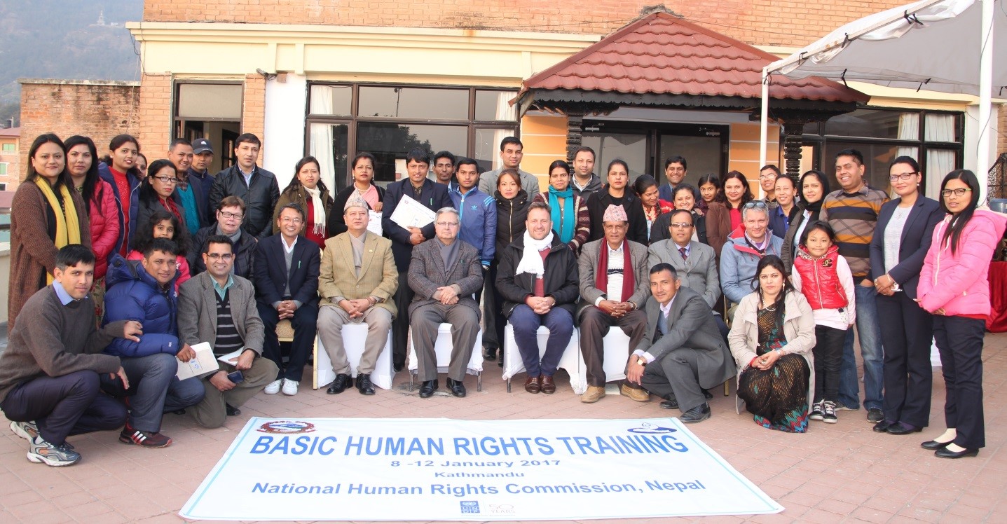 Un gruppo di donne e uomini in posa per una foto attorno a uno striscione che riporta il titolo della formazione («Basic human rights training»).