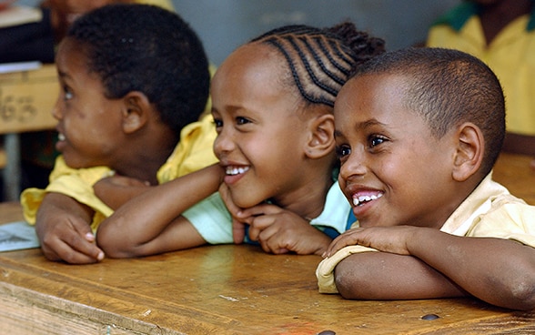 Zwei Buben und ein Mädchen an einem Pult in einer Schule in Äthiopien. 