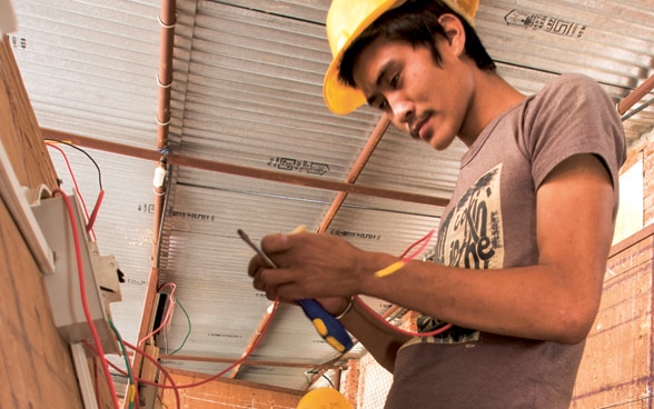 Three young apprentices training to be electricians in Nepal.