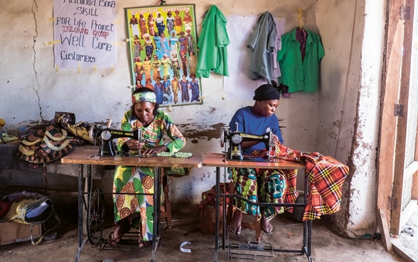 Due donne sedute a un tavolo intente a lavorare alla macchina da cucire in Kenya.