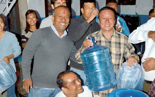 Una decina di persone con distributori e bottiglie d’acqua in Nepal.