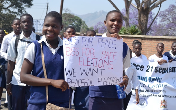 Junge Menschen mit Plakaten an einer Kundgebung für Frieden und friedliche Wahlen in Malawi. 