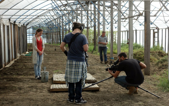 La imagen muestra la puesta en escena donde Medea riega brotes jóvenes de tomates.