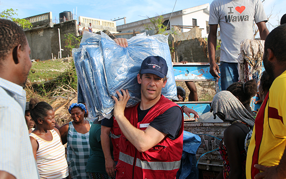 Un esperto svizzero distribuisce teloni alla popolazione haitiana.