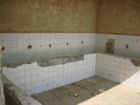 Restroom with taps removed and broken tiles