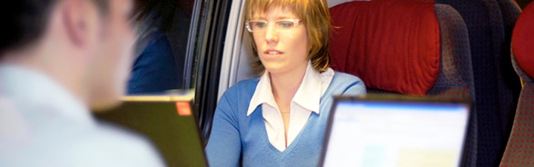 Eine Frau und ein Mann arbeiten im Zug am Computer