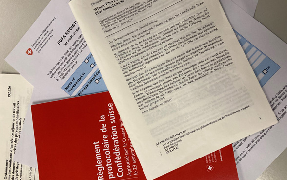 Différents documents, tels que la Convention de Vienne sur les relations consulaires, posés sur une table.