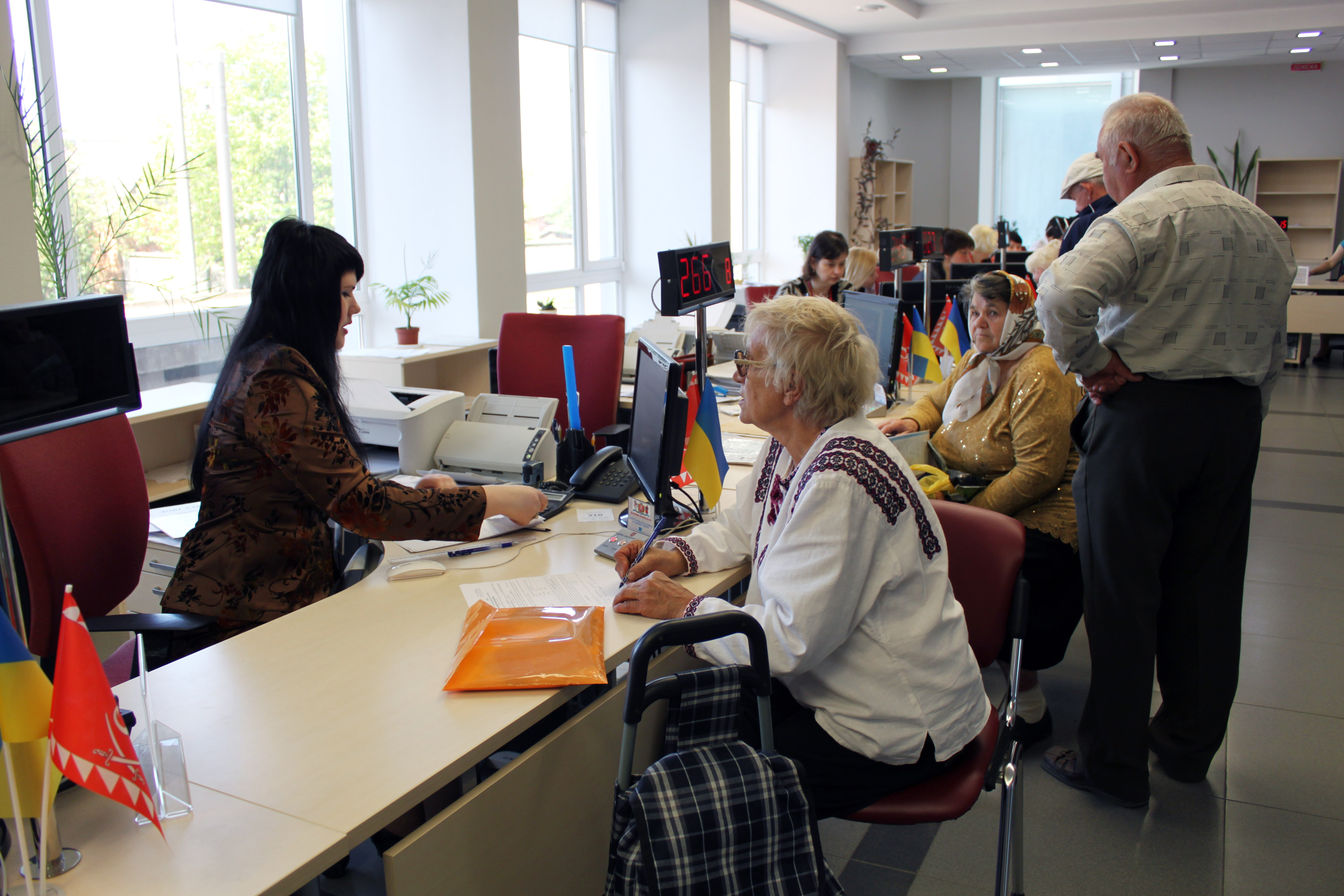 Des employés assis à leur poste de travail parlent avec des usagers.