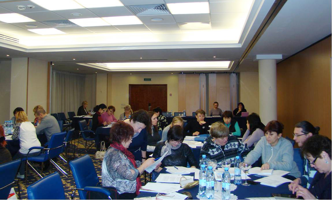 A group of people sitting around a table in a classroom studying documents.