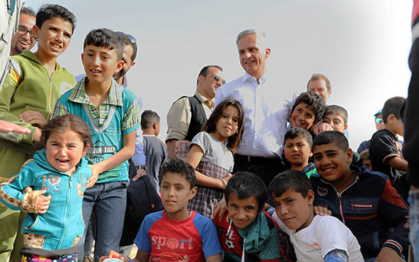 A crowd of refugee children standing next to the head of the FDFA