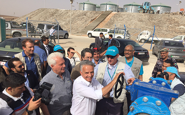 Il consigliere federale Didier Burkhalter gira una ruota che mette in funzione la rete di acqua potabile nel campo di Azraq.