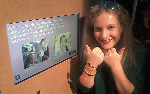 A teenage girl poses in front of a screen simulating interactive dialogue with a young Kyrgyz girl. © FDFA