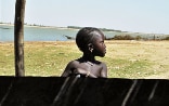 Primo piano di una bambina; sullo sfondo, il fiume Niger.