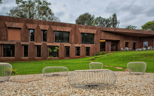 Reddish brown embassy building in Nairobi with seating in the foreground.