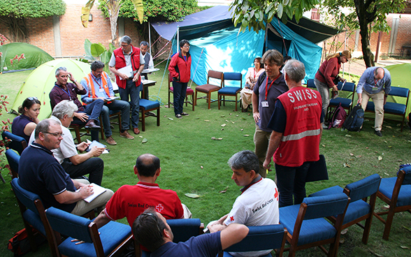 La squadra di pronto intervento dell'Aiuto umanitario della Confederazione discute con rappresentanti di ONG nel giardino dell'Ambasciata di Svizzera in Nepal.