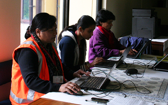 Collaboratori locali dell’Ambasciata di Svizzera in Nepal lavorano, seduti a un tavolo. 