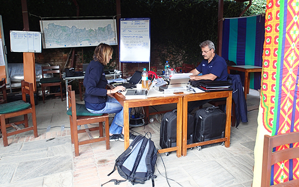 Two members of the Swiss Humanitarian Aid rapid response team working at a desk.
