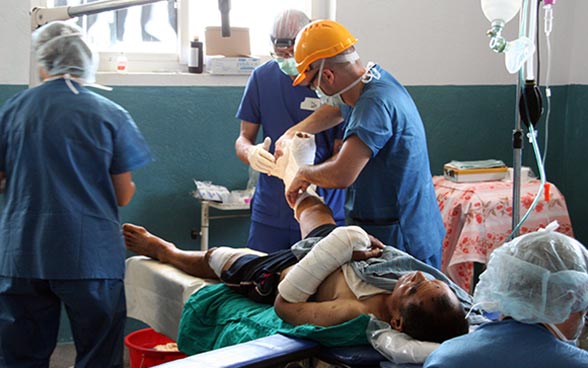 Three doctors treating a patient.