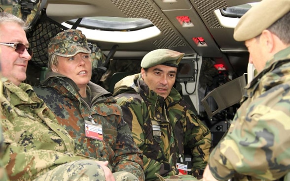 Vier Personen in Militärbekleidung sitzen in einem Helikopter