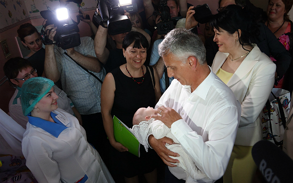 Didier Burkhalter prendre in braccio un neonato.