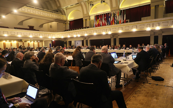 Delegates at the second plenary meeting of the IHRA in a hall.