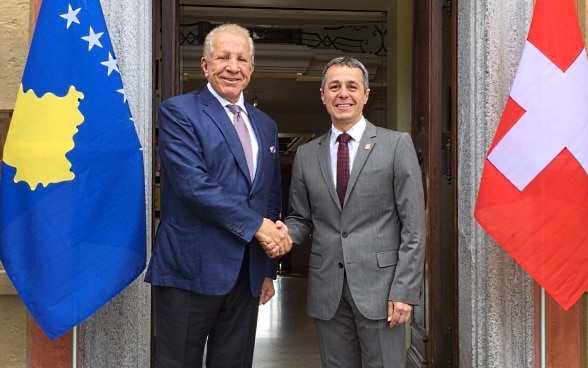 Bundesrat Ignazio Cassis und der kosovarische Aussenminister Behgjet Pacolli sitzen an einem kleinen Tisch und unterhalten sich.