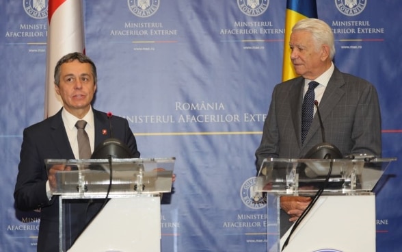 Rencontre entre le Conseiller fédéral Cassis et le ministre roumain des affaires étrangères Teodor Meleșcanu. En arrière-plan se trouvent les drapeaux de la Roumanie et de la Suisse.