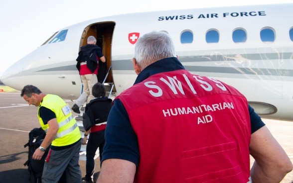 Des experts du Corps suisse d'aide humanitaire (CSA) montent à bord d'un avion de la Confédération suisse à Belp.