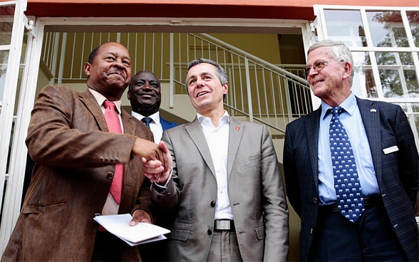 Federal Councilor Ignazio Cassis shakes hands with Zimbabwean Minister of Health Obadiah Moyo, left, while Professor Ruedi Luthy, founder of a Swiss-funded clinic, looks on during his visit.