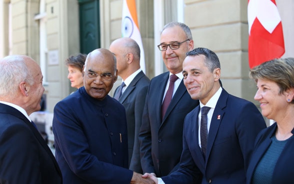 Il presidente indiano e Ignazio Cassis stringono la mano in presenza dell'intero Consiglio federale.