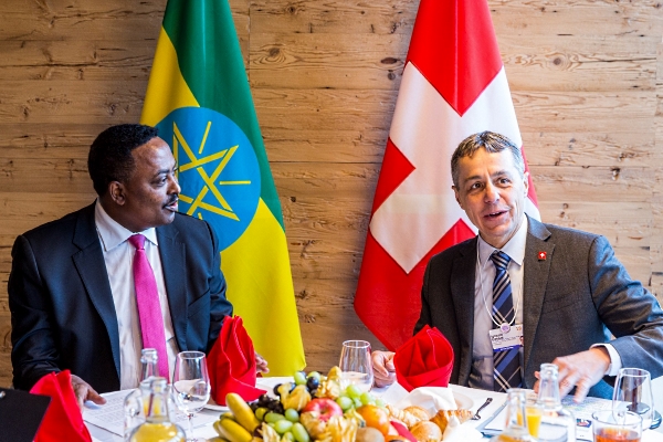 Il consigliere federale Cassis è seduto a un tavolo riccamente decorato in conversazione con il ministro degli esteri etiope Gebeyehu. Sullo sfondo si vedono le bandiere della Svizzera e dell'Etiopia.